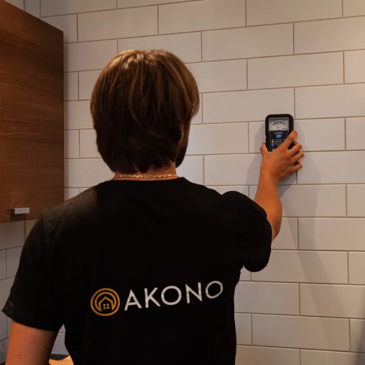 Akonos tekniker mäter med ett instrument mot väggen